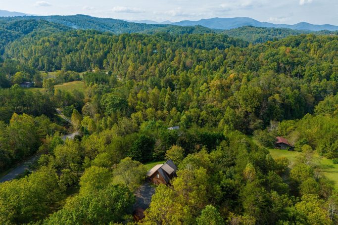 Aerial view of a lush green landscape with scattered homes and rolling hills.