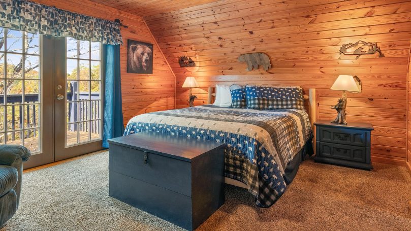 Cozy wooden bedroom with a blue and white patterned bedspread and balcony access.