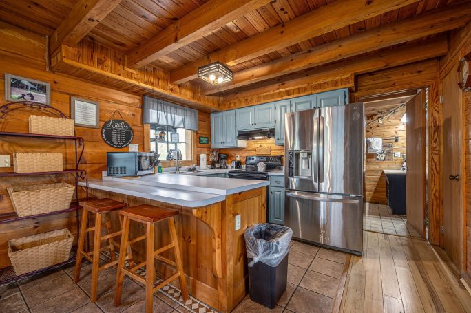 Cozy rustic kitchen with blue cabinets, wooden accents, and stainless steel appliances.