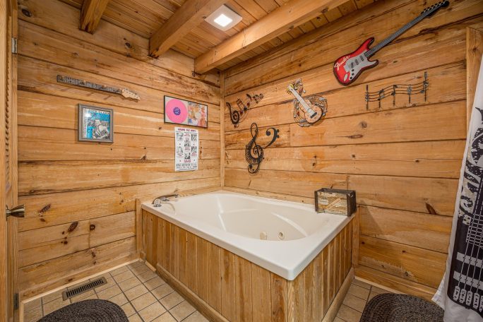 Rustic bathroom with a wooden wall, a jetted tub, and musical decor.