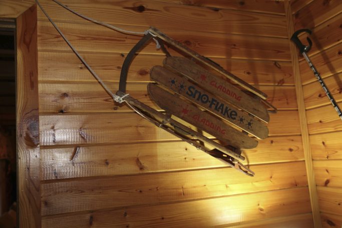 Wooden sled hanging on a wall in a rustic cabin setting.